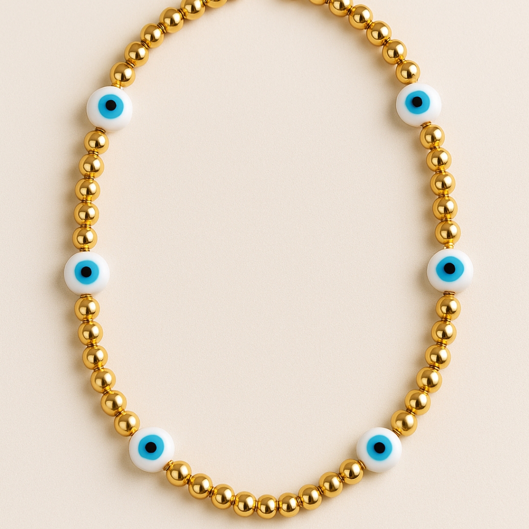 Collar dorado con cuentas de ojo turco blanco y azul sobre fondo claro, joyería elegante y protectora
